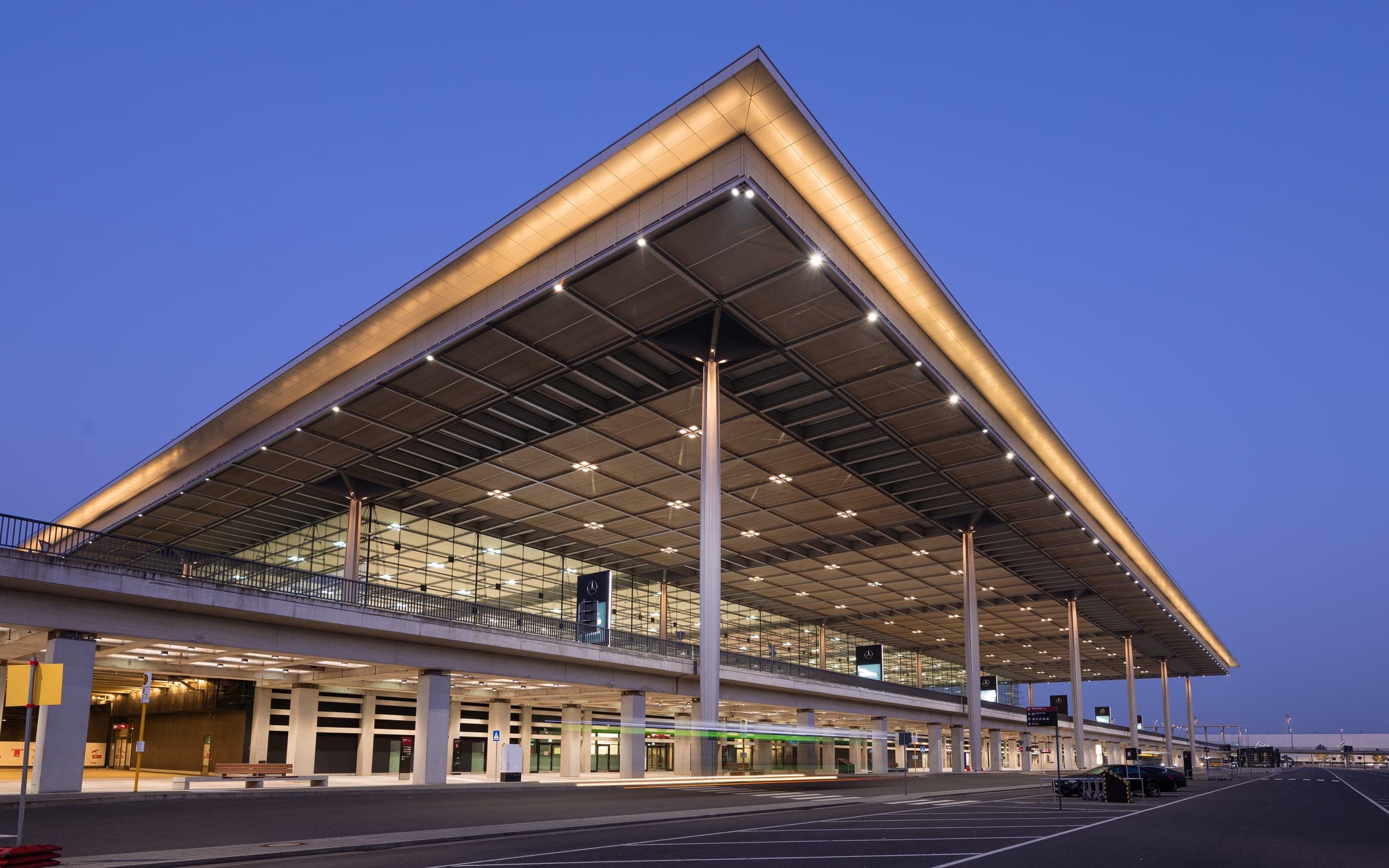 Terminal 1 des Flughafens Berlin Brandenburg mit dem weit auskragenden, beleuchteten Dach zur blauen Stunde