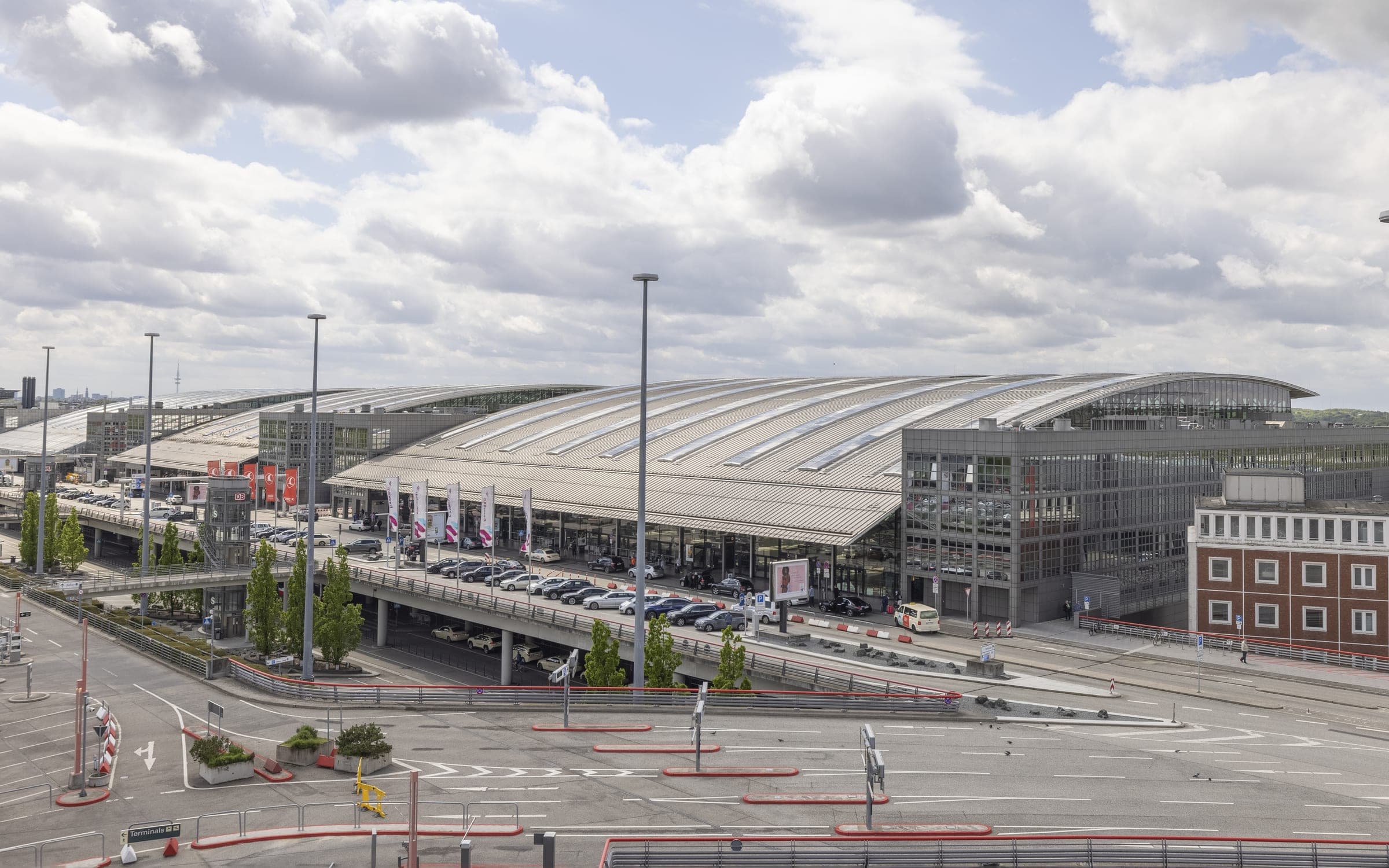 Terminals des Flughafens Hamburg mit den geschwungenen Dächern und der Vorfahrt bei bewölktem Himmel